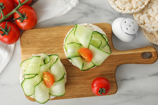 Puffed rice cakes with vegetables served on white marble table, flat lay - 写真・画像