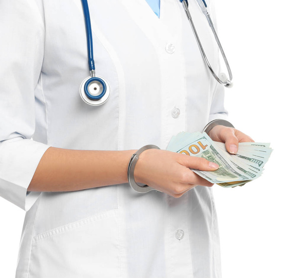 Doctor in handcuffs with bribe on white background, closeup. Cor - Photo, image