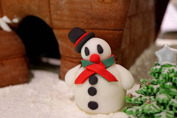 Закрийте лагідного сніговика Marzipan з будинком для хліба Ginger і ялинкою для цукерок - Фото, зображення