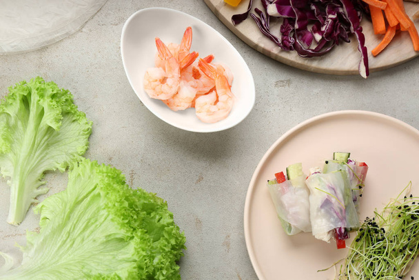 Flat lay composition with delicious rolls wrapped in rice paper on light grey table - Foto, Imagen