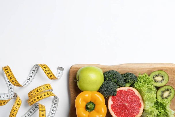 Fruits, vegetables and measuring tape on white background, top view. Visiting nutritionist - Foto, imagen