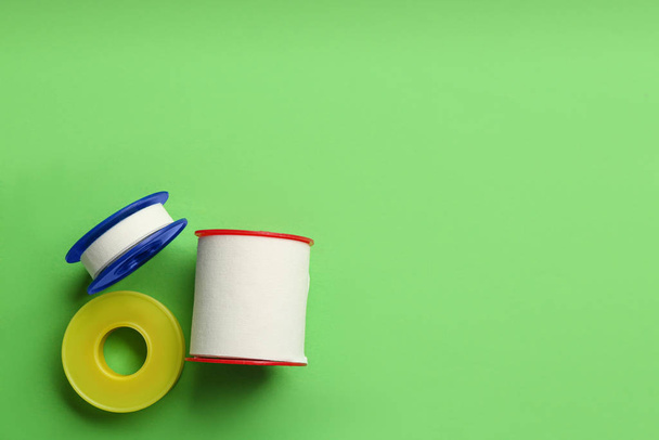 Sticking plaster rolls on green background, flat lay. Space for text - Foto, Bild