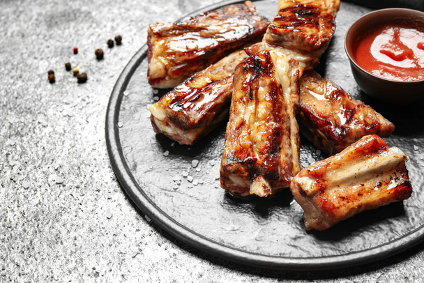 Board with delicious ribs on grey table, closeup - Photo, Image