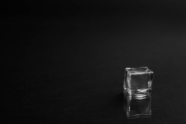 Crystal clear ice cube on black background. Space for text - Foto, afbeelding