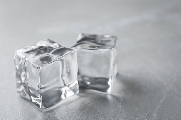 Crystal clear ice cubes on grey table, closeup - Foto, afbeelding