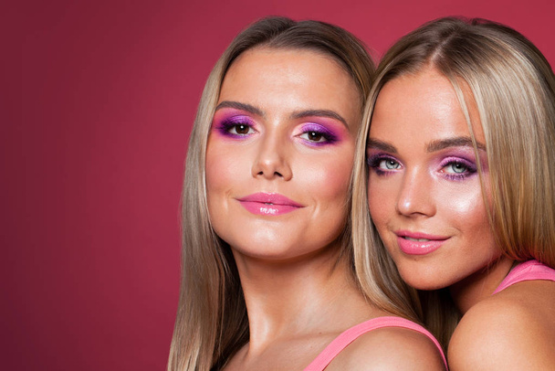 Mooie glimlachende vrouwen modellen met make-up op roze - Foto, afbeelding