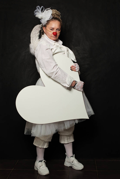 White clown woman with white empty heart banner on black background - Foto, immagini