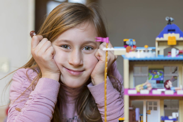 Κοριτσάκι που παίζει με παιδιά κατασκευάστρια στο σπίτι. Κοριτσάκι παίζει με πολύχρωμα πλαστικά μπλοκ κατασκευαστή και κτίριο σπίτι. - Φωτογραφία, εικόνα
