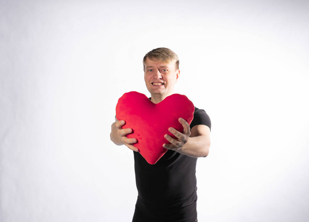 The guy is holding in his hands a heart for the happiness of Valentines day on white background - Photo, Image