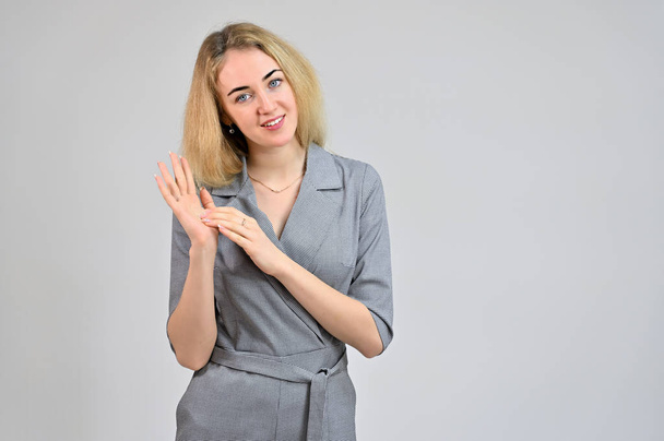Portrait of a pretty cute smiling young blonde business woman with minimal makeup in a gray suit on a white background. Model Standing directly in front of the camera in various poses. - Foto, afbeelding