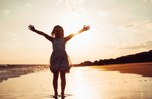Happy children having fun on the beach at sunset - Rozkošné malé dítě roztahuje ruce podél pobřeží - Dětství, svoboda a štěstí koncept - Sytost filtr - Fotografie, Obrázek
