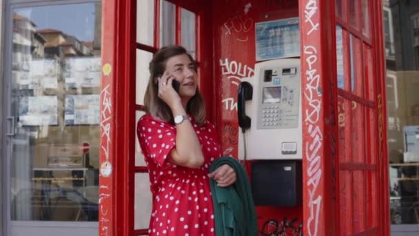 Νεαρή γυναίκα, φοιτητής μιλάει στο κινητό τηλέφωνο σε τηλεφωνικό θάλαμο - Πλάνα, βίντεο