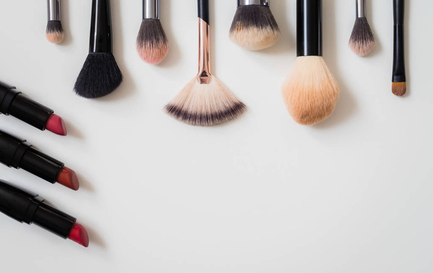 Set of makeup brushes and other accessories. Lipstick, mascara, nail polish, eyeshadow, powder, eyelash and foundation. Products for makeup on white background, top view.  - Foto, imagen