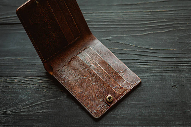 шкіряне ремесло ручної роботи старовинний коричневий порожній гаманець на чорному дерев'яному фоні. Фінанси, бідність, грошова концепція
 - Фото, зображення