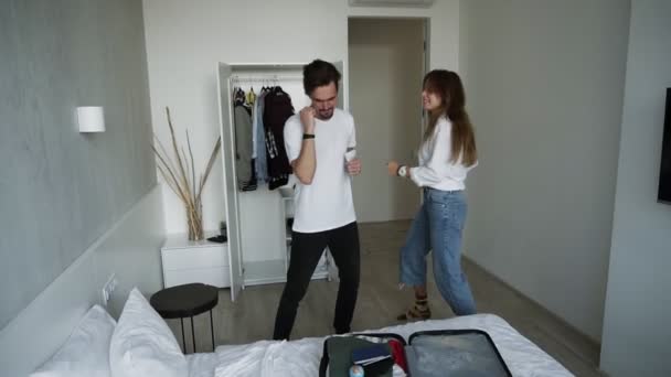 Two cool modern persons having fun together on vacation or before. Young good-looking funny couple in love dancing together in hotel. Happy lifestyle. Travel. Suitcase in forefront - Footage, Video