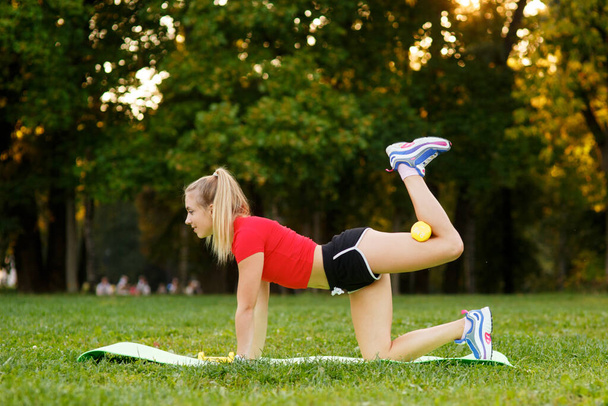 Healthy young sportswoman doing the exercises on all fours arching back straightening leg up outdoors. Concept sport, fitness, lifestyle. - Foto, Imagem