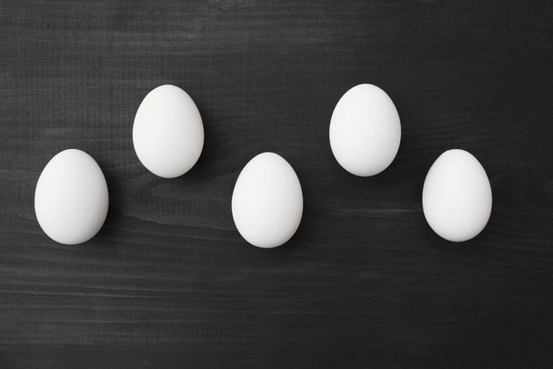 Белые яйца на столе, на черном деревянном фоне
. - Фото, изображение