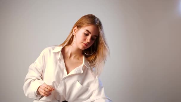 junges blondes hübsches Teenie-Mädchen im weißen Hemd spricht im Studio über Make-up - Filmmaterial, Video