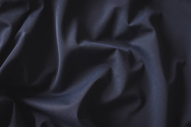 Folded dark blue woolen fabric textile close up for background.  - Fotó, kép