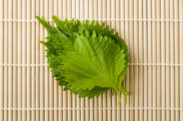 friss zöld shiso (perilla) vagy oba levél bambusz hengerelt szőnyegen - Fotó, kép