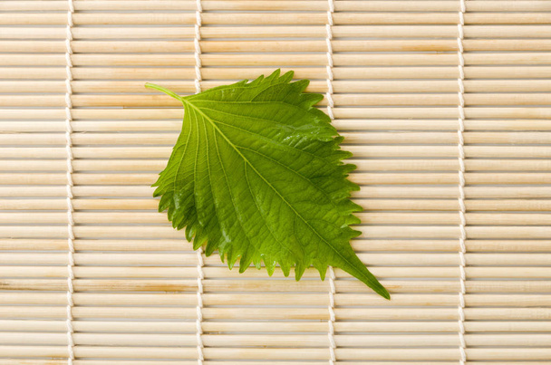 friss zöld shiso (perilla) vagy oba levél bambusz hengerelt szőnyegen - Fotó, kép