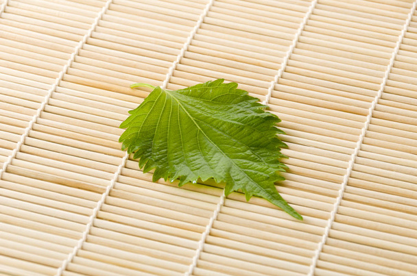 Свежий зеленый шисо (перилла) или лист оба на бамбуковом коврике
 - Фото, изображение
