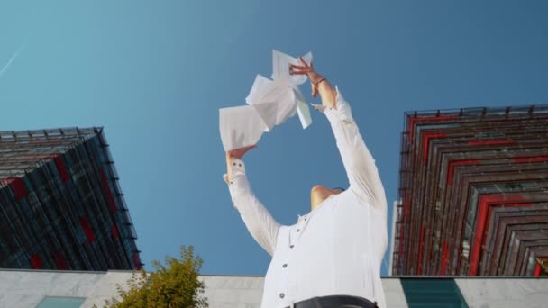 SLOW MOTION: Gelukkige jongeman gooit papieren in de lucht na het krijgen van promotie. - Video