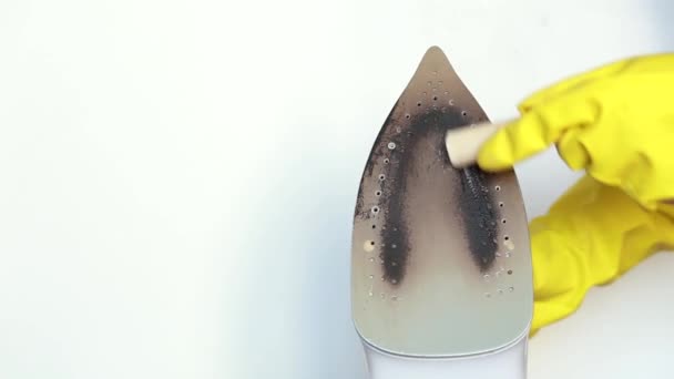 Le mani femminili in guanti gialli puliscono la superficie sporca del ferro con una matita speciale. Video.
 - Filmati, video