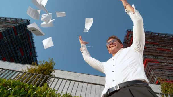 Nahaufnahme: Papiere fliegen in die Luft, als lächelnder Geschäftsmann seine Beförderung feiert. - Filmmaterial, Video