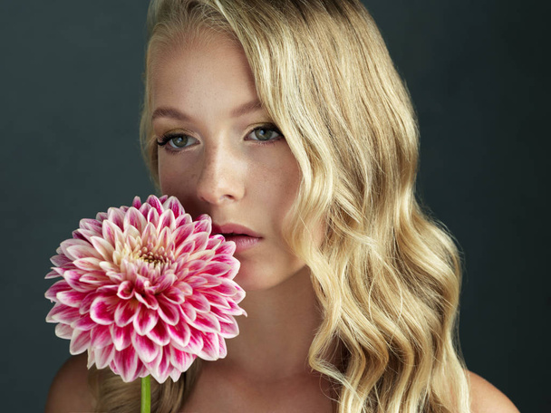 Portret blondynki z niesamowitym dużym kwiatem na szarym tle - Zdjęcie, obraz