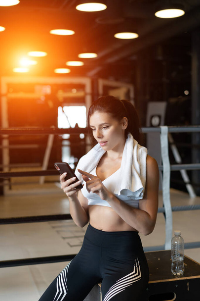 Mädchen, die während einer Pause in einem Fitnessstudio SMS schreiben. liest eine Nachricht - Foto, Bild