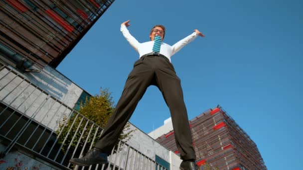 LOW ANGLE: Fröhlicher Geschäftsmann springt auf und streckt nach der Arbeit die Arme aus. - Filmmaterial, Video