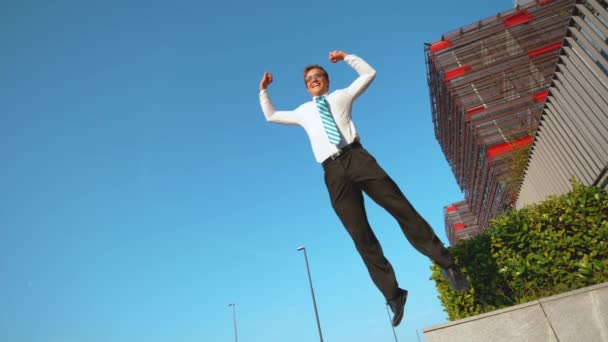 Slow Motion: Vrolijke zakenman springt van een betonnen richel met uitgestrekte armen - Video