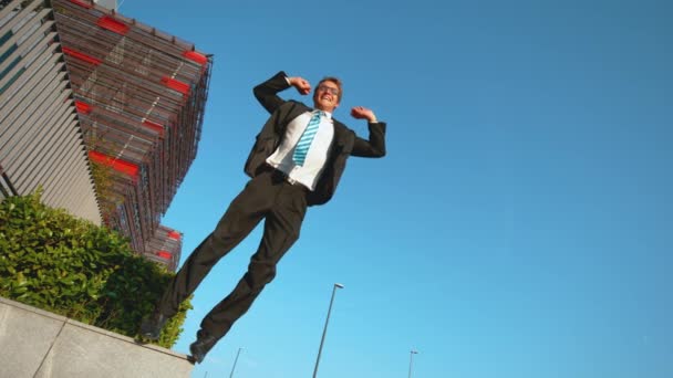 Slow Motion: Bedrijfsprofessional springt van de richel en hoog in de lucht. - Video