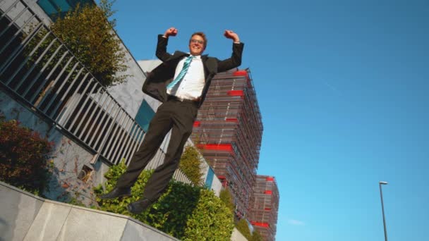 LOW ANGLE Ecstatic Kaukasische zakenman springt in de lucht met uitgestrekte armen - Video