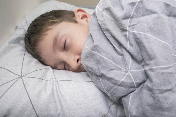 A preteen kid boy sleeping in bed at home, bedtime and sweet dreams concept - Fotografie, Obrázek