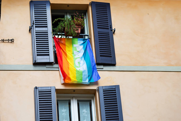 La bandera de lgbt colores y la palabra Pease en italiano colgando en la fachada del edificio, Bérgamo
 - Foto, imagen