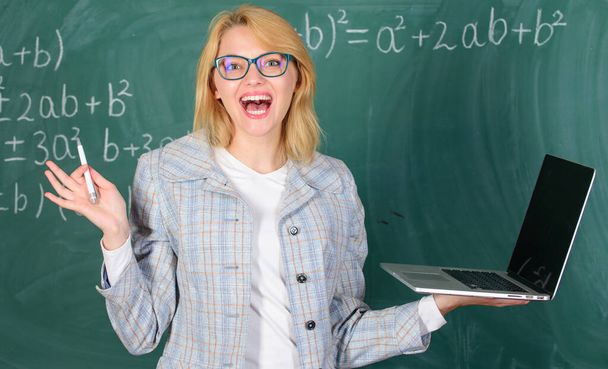 Woman teacher wear eyeglasses holds laptop surfing internet. Digital technologies concept. Educator cheerful lady with modern laptop surfing internet chalkboard background. Education is fun - Fotó, kép