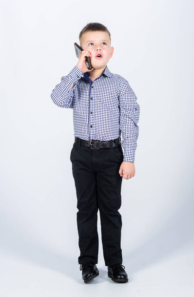 Little boy formal clothes call mobile phone. Cute boy hold smartphone. Mobile conversation. Mobile communication. Modern gadget. Small businessman. Business school. Upbringing and development - 写真・画像
