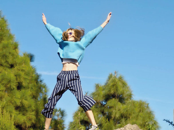 Giovane donna salta in aria con le braccia tese
  - Foto, immagini