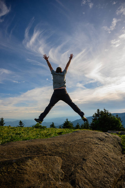 Man springt over groene bergketen - Foto, afbeelding