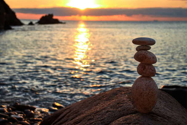 Ισορροπημένες πέτρες το ξημέρωμα δίπλα στη θάλασσα - Φωτογραφία, εικόνα