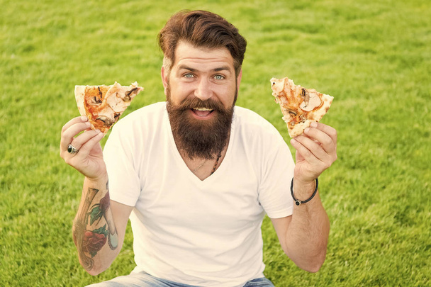 Both pieces for me. Man bearded hipster eating delicious pizza. Cheerful guy eat pizza. Summer picnic concept. Caucasian male loving Italian traditional food. Hungry greedy man hold pizza in hands - Valokuva, kuva