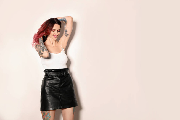 Beautiful woman with tattoos on body against light background. Space for text - Fotó, kép