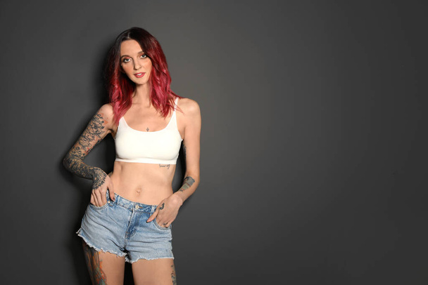 Beautiful woman with tattoos on body against black background. Space for text - Zdjęcie, obraz