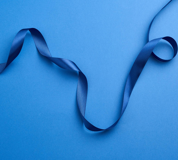 blue silk thin ribbon twisted on a blue background - Foto, imagen