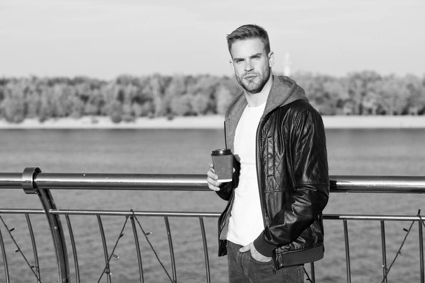 Idyllic morning. Hipster hold paper coffee cup. Coffee break. Drink it on go. Man hipster hold coffee take away riverside background. Handsome guy drink coffee outdoors. Rituals determine personality - Photo, image
