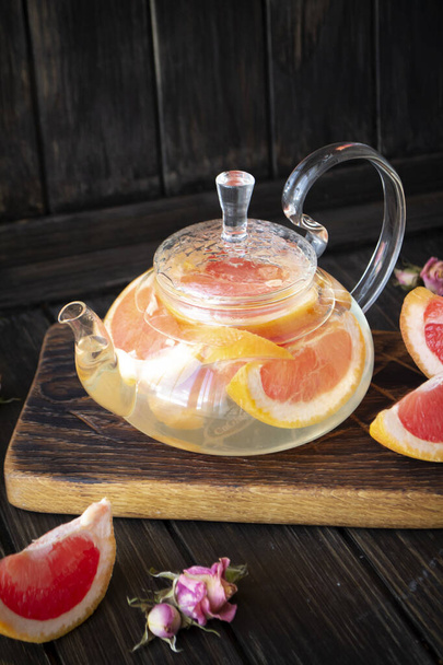 Glass teapot with grapefruit tea on dark rustic background - Foto, Bild