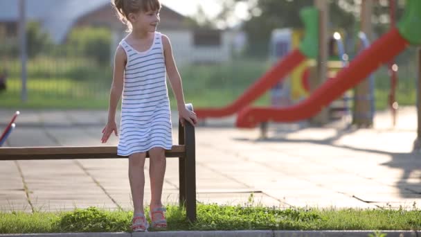 Anaokulunun bahçesinde yaz parkında bir bankta oturan üzgün çocuk annesini bekliyor.. - Video, Çekim