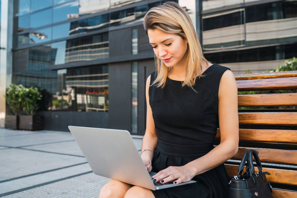 Business woman using her laptop outdoors. - Photo, image